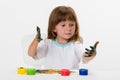 Close-up portrait of a cute cheerful happy smiling little girl draws her own hands with gouache or finger paints isolated on white Royalty Free Stock Photo