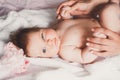 Close-up portrait of cute happy smiling baby girl lying down on bed. Mother is holding her newborn baby. Small daughter Royalty Free Stock Photo