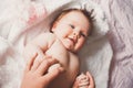 Close-up portrait of cute happy smiling baby girl lying down on bed. Mother is holding her newborn baby. Small daughter Royalty Free Stock Photo