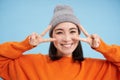Close up portrait of cute korean girl in beanie, shows peace, vsign gesture, positive vibe, smiling and laughing, posing Royalty Free Stock Photo