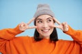 Close up portrait of cute korean girl in beanie, shows peace, vsign gesture, positive vibe, smiling and laughing, posing Royalty Free Stock Photo
