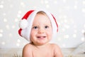 Close up portrait of a cute little baby with red Santa Claus hat. Lights on background. Small smiling kid face. Royalty Free Stock Photo