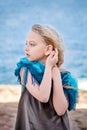 Close-up portrait of a cute little blonde girl staring into the far sea dreamily posing with her hands near her ear Royalty Free Stock Photo