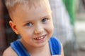 Close up portrait of cute little Caucasian boy with blond hair and blue eyes, smiling. Casual summer wear, happiness and joy of ch