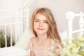 Close-up portrait of a cute little girl. Portrait of a beautiful little girl with long blonde hair on the bed in a bright bedroom Royalty Free Stock Photo