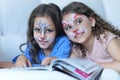 Cute little girls with faces painted reading magazine Royalty Free Stock Photo