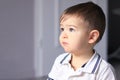 Close up portrait of cute little thoughtful baby boy in white shirt daydreaming at home. Royalty Free Stock Photo