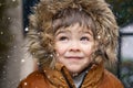 Close up portrait of cute little toddler boy in furry hood looking at snowfall Royalty Free Stock Photo