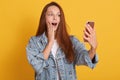 Close up portrait of cute lovely woman taking selfie, posing over yellow background, lady with open mouth holding her mobile phone Royalty Free Stock Photo