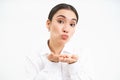 Close up portrait of cute office lady sends air kiss on palms, puckers lips and looks tender at camera, stands over Royalty Free Stock Photo