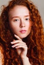 close up portrait of cute red-haired girl on beige background. Beautiful long curly hair, no makeup Royalty Free Stock Photo