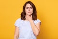Close up portrait of cute sick young brunette woman wearing white casual t shirt, having sore throat, holding hand on her neck, Royalty Free Stock Photo