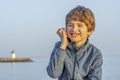 Little boy holding a seashell close to his ear.little boy with shell listening noise of sea. sea in out of focus Royalty Free Stock Photo