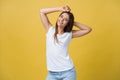 Close-up portrait of cute young woman relaxing with hand behind head. Isolated over yellow background. Royalty Free Stock Photo