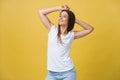 Close-up portrait of cute young woman relaxing with hand behind head. Isolated over yellow background. Royalty Free Stock Photo