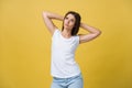 Close-up portrait of cute young woman relaxing with hand behind head. Isolated over yellow background. Royalty Free Stock Photo