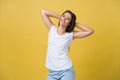 Close-up portrait of cute young woman relaxing with hand behind head. Isolated over yellow background. Royalty Free Stock Photo