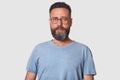 Close up portrait of dark haired serious young male with beard, man looks confidently at camera, dressed casual gray t shirt and Royalty Free Stock Photo