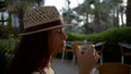 Close-up portrait of a dark-haired woman in a hat, she is middle-aged, who drinks a drink from a glass glass, she smiles Royalty Free Stock Photo