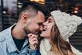 Close-up portrait of debonair woman in knitted hat playfully posing with boyfriend. Cute european couple fooling around