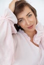 Close-up portrait of delightful young woman with long hair in dress made of natural linen with pink ruffles.