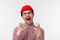 Close-up portrait of distressed and angry young funny hipster guy with moustache wear red beanie, glasses, squeez hands Royalty Free Stock Photo