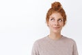 Close-up portrait, dreamy gorgeous and feminine redhead woman with curly hair combed in messy bun, smiling carefree