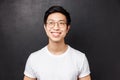 Close-up portrait of dreamy happy young asian man in white t-shirt, glasses, beaming smile excited, looking left Royalty Free Stock Photo