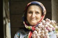 Portrait of an elderly woman having bunch of garlic toots on her shoulder