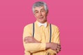 Close up portrait of eldery man with yellow shirt and white bow tie, looking directly at camera, keeps hands folded, free spase