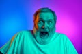 Close-up portrait of emotional bearded senior man with wide open mouth and eyes expressing shock on gradient blue-purple Royalty Free Stock Photo