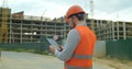 Close-up portrait of engineer with gadget on background of building under construction. Modern construction engineer or Royalty Free Stock Photo