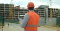 Close-up portrait of engineer with gadget on background of building under construction. Modern construction engineer or Royalty Free Stock Photo