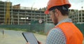 Close-up portrait of engineer with gadget on background of building under construction. Modern construction engineer or Royalty Free Stock Photo