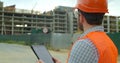 Close-up portrait of engineer with gadget on background of building under construction. Modern construction engineer or Royalty Free Stock Photo