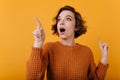 Close-up portrait of enthusiastic girl with suprised face expression looking around. Studio shot of lovable curly lady Royalty Free Stock Photo