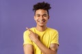 Close-up portrait of enthusiastic, happy young hipster male with dreads, beaming smile and pointing finger upper left