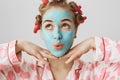 Close-up portrait of european girly girl with cute expression, wearing pyjamas and hair-curlers, standing with facial Royalty Free Stock Photo