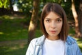 Close-up portrait European young brunette student female outdoor, wearing white t-shirt and denim jacket Royalty Free Stock Photo