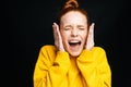 Close-up of excited angry young woman screaming with closed eyes on isolated black background.