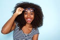 Close up excited young african american woman with curly hair wearing glasses on blue background Royalty Free Stock Photo