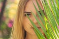 Close up portrait face blond woman thick eyebrows like Cara Delevingne with palm branch