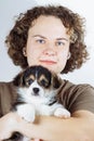 Close-up portrait of face of charming woman, owner of small Welsh corgi puppy, whom she holds in her arms. Dog food. Royalty Free Stock Photo