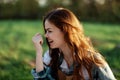 Close-up portrait of the face of a smiling, beautiful redheaded young woman in nature in a green park at sunset Royalty Free Stock Photo