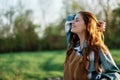 Close-up portrait of the face of a smiling, beautiful redheaded young woman in nature in a green park at sunset Royalty Free Stock Photo