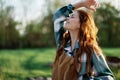 Close-up portrait of the face of a smiling, beautiful redheaded young woman in nature in a green park at sunset Royalty Free Stock Photo