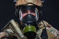 Close up portrait of the face and tired eyes of a soldier standing in a military helmet and gas mask, ready for a