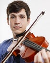 Close-up portrait of face of young violinist playing instrument and looking at camera. Melancholic expression. Concept of music,