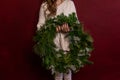 Close up portrait faceless young woman in knitted white sweater holds green Christmas wreath in hand Royalty Free Stock Photo