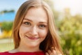 Close-up portrait of fair-haired woman with green alluring eyes, freckles smiling having dimples on cheeks looking happily directl